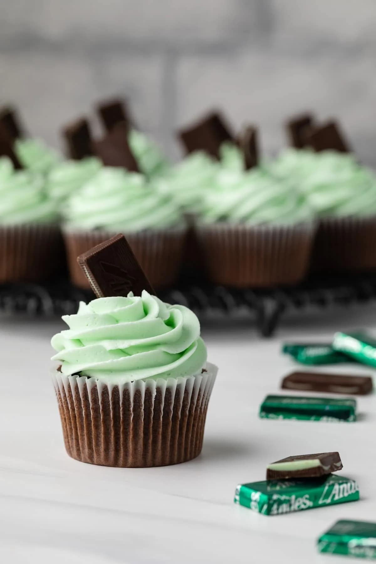 Chocolate cupcakes topped with mint buttercream frosting and a piece of chocolate bar.