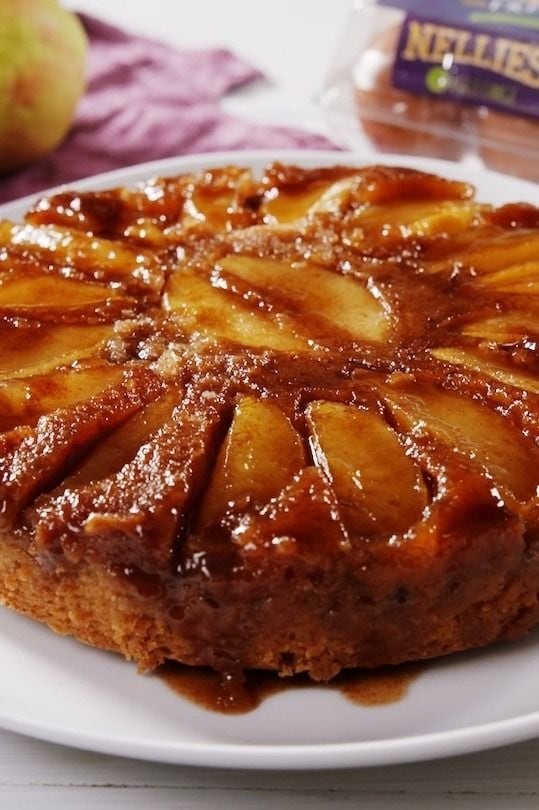 Apple upside cake with syrup served on a white plate. 