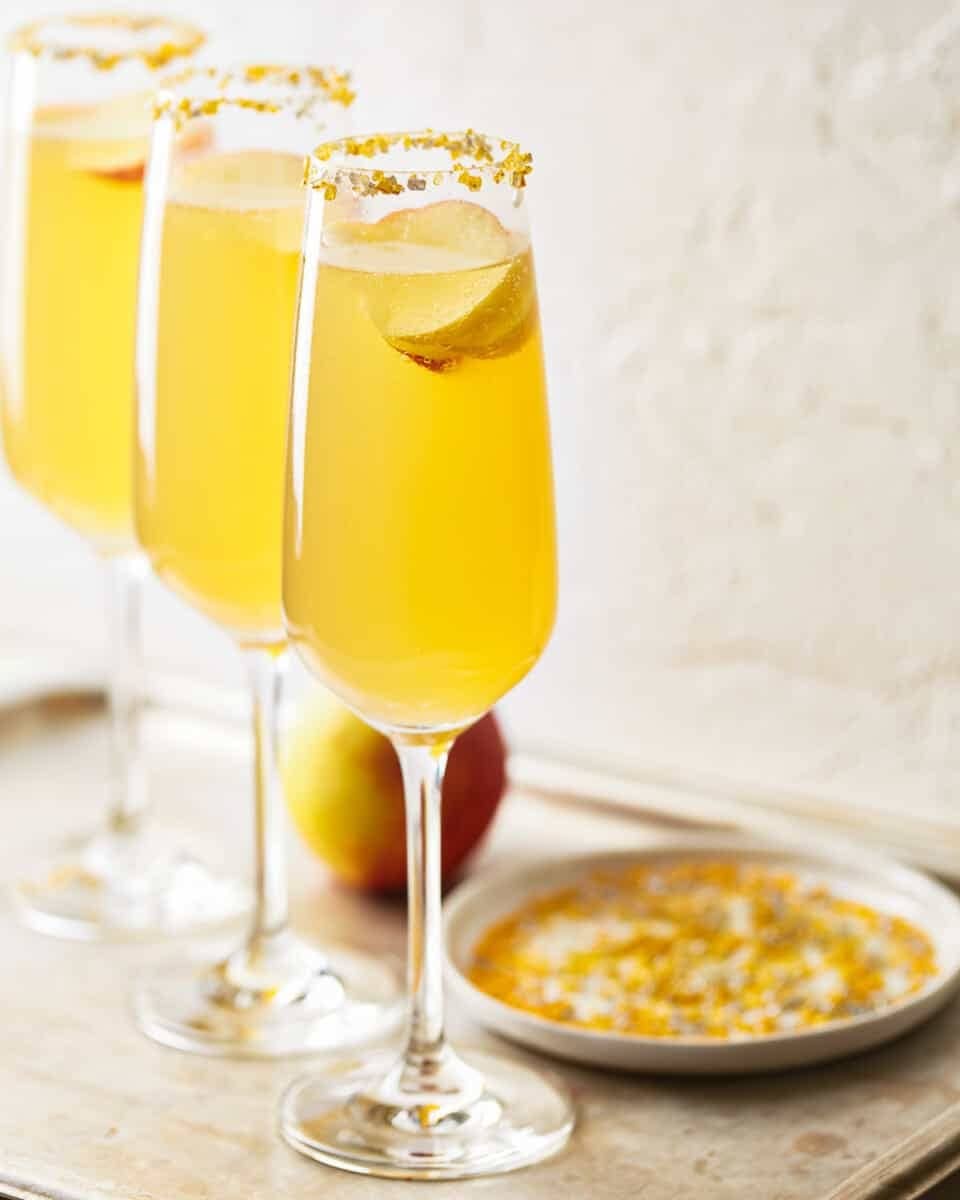 Apple cider mimosa cocktails on gold sprinkles rimmed glasses. 