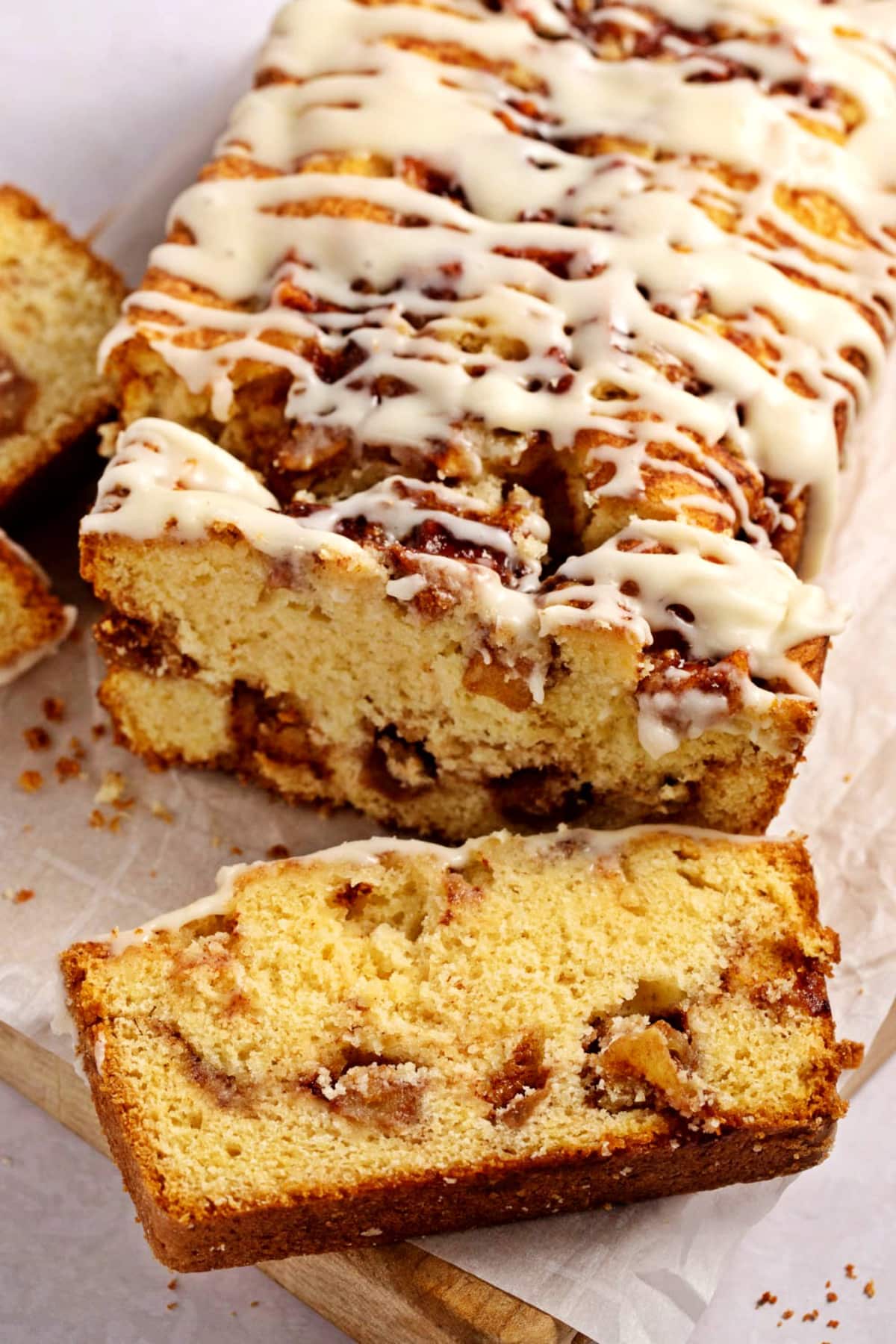 Sliced apple fritter loaf bread drizzled with white sugar glaze. 