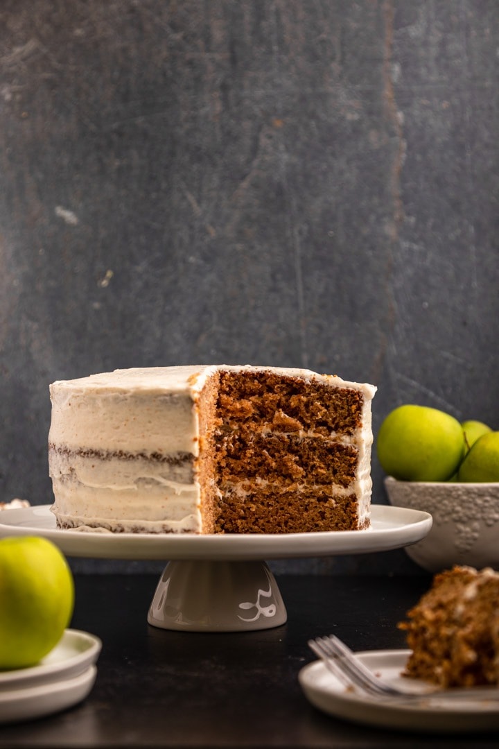 Sliced apple layer cake with frosting on a cake tray.