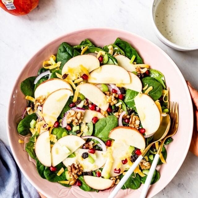 Salad with sliced apple, walnut, basil leaves, pomegranate aril and cheese.