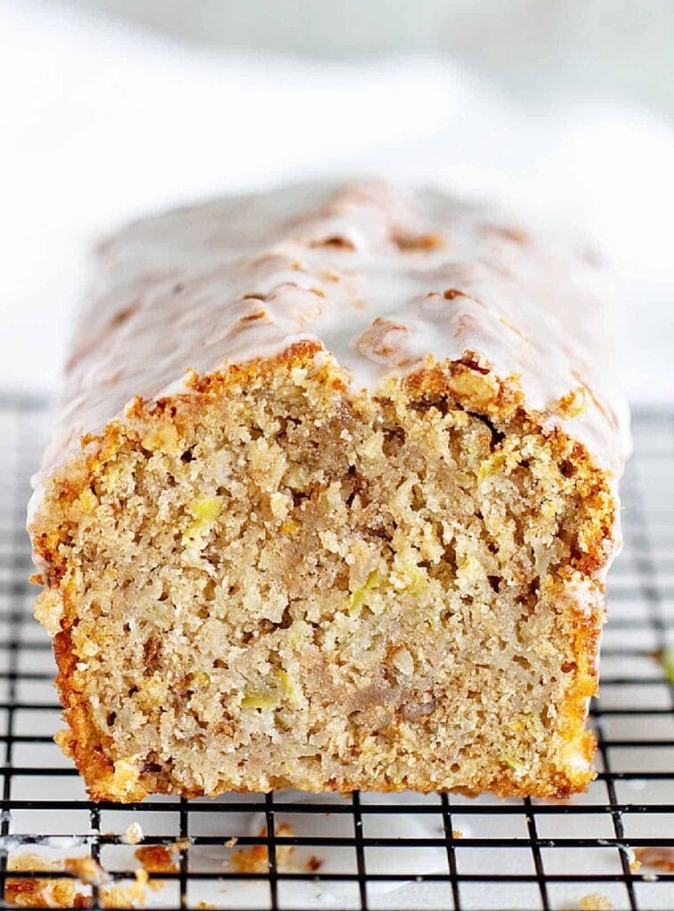 Apple and walnut loaf covered with sugar glaze on a cooling rack.