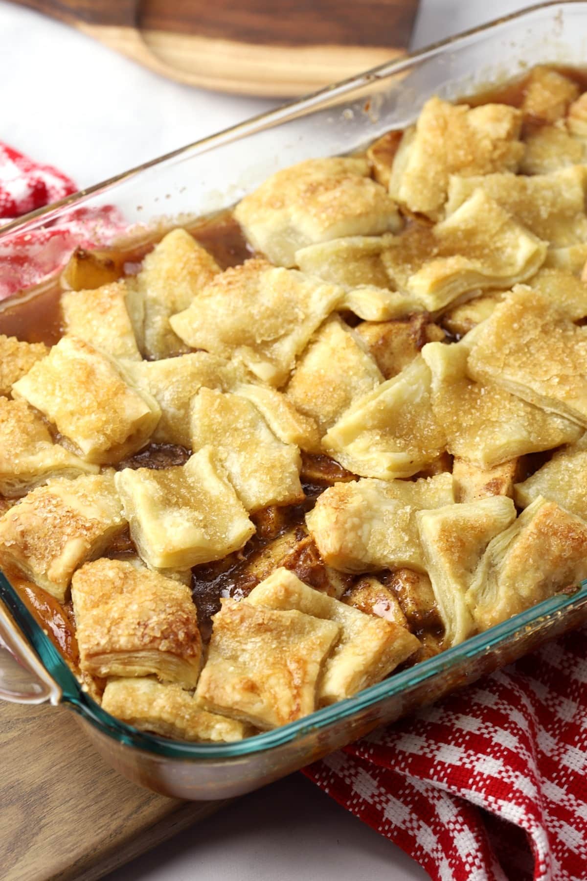 Apple pie in a glass baking dish, with golden crust and bubbling filling, ready to be served.