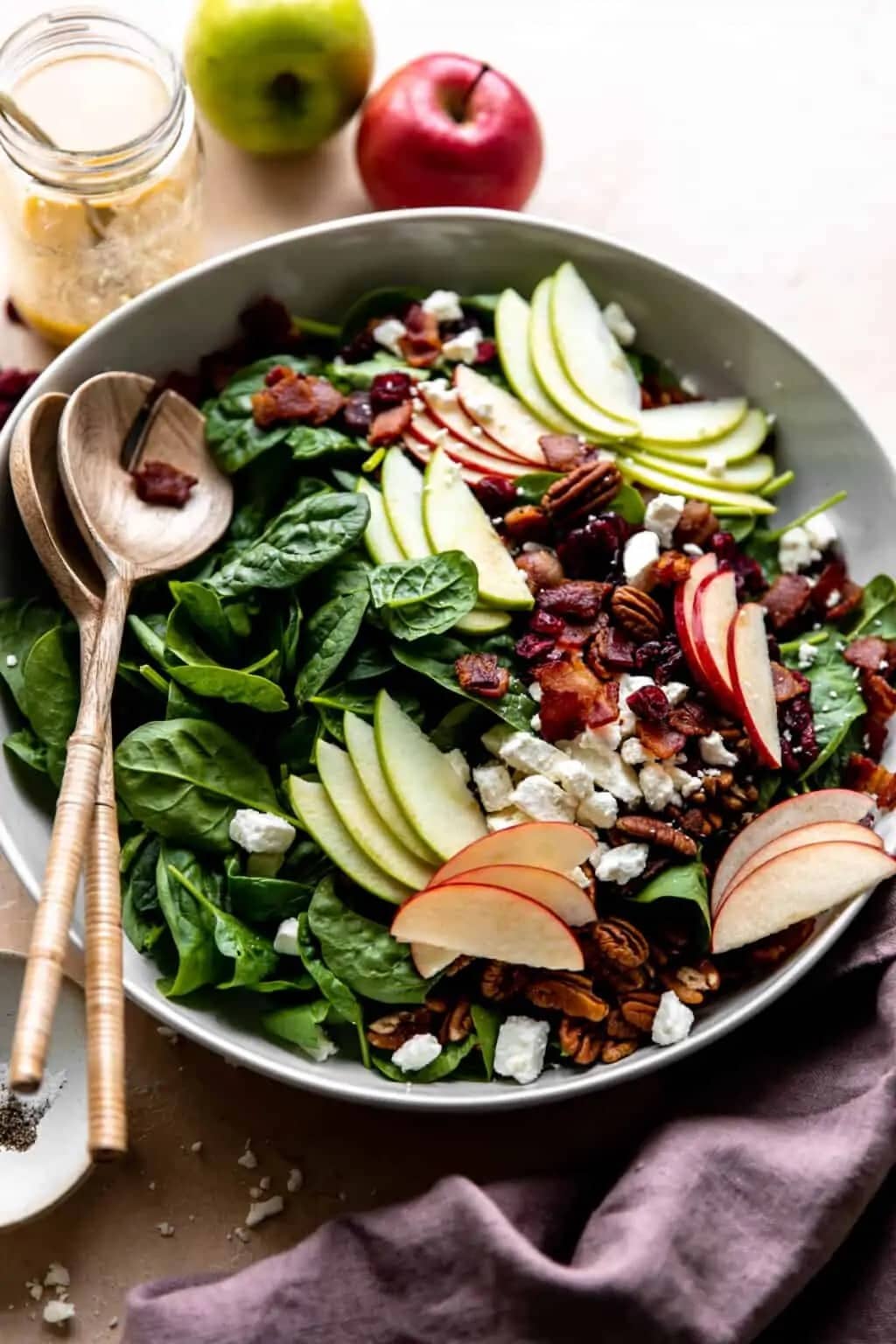 Autumn apple salad made with pecans, cranberries, apples, feta and baby spinach layered on top of fresh spinach.