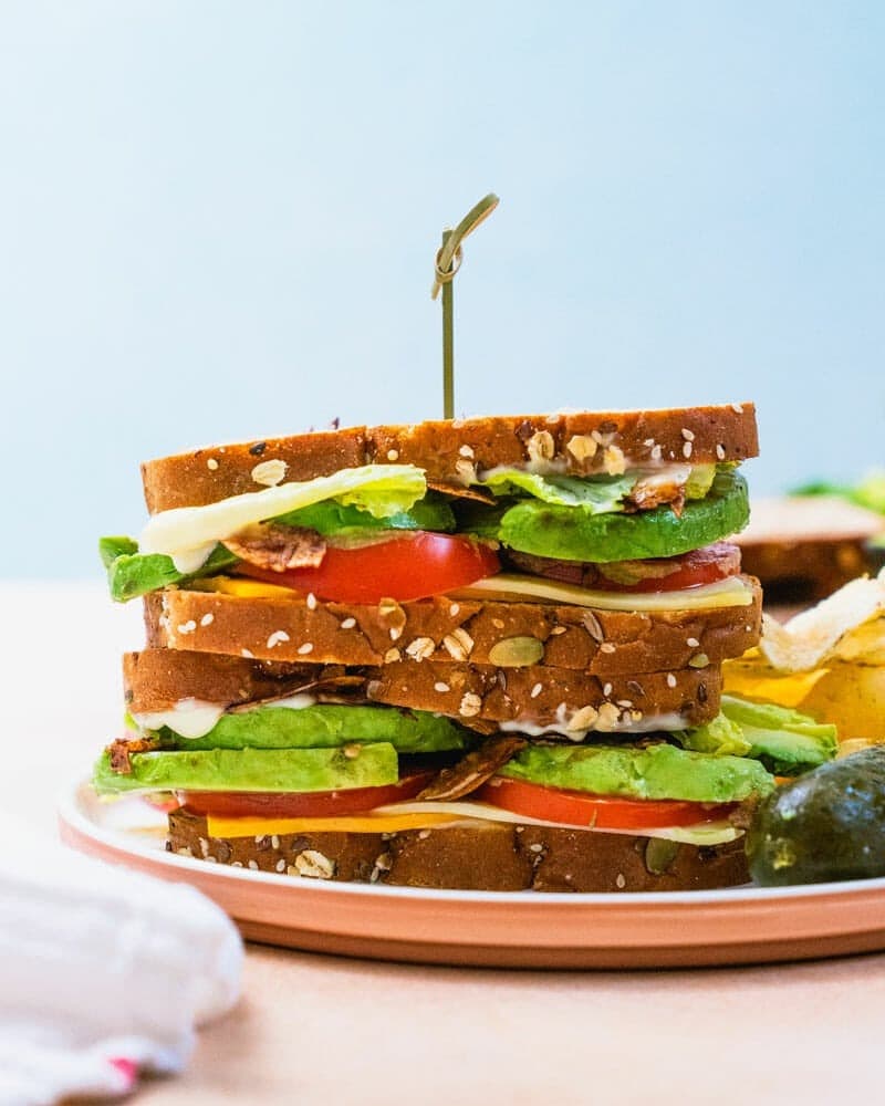 Sandwich with turkey, sliced avocado, tomato, lettuce filling. 
