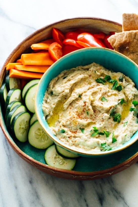 Baba ganoush in a bowl served with slices of cucumber, bell pepper and carrots on the sides. 