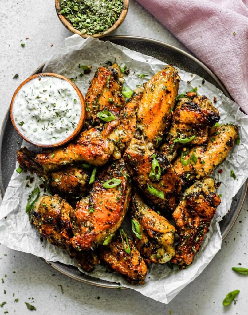Baked chicken wings seasoned with herbs and spices served with dipping sauce. 
