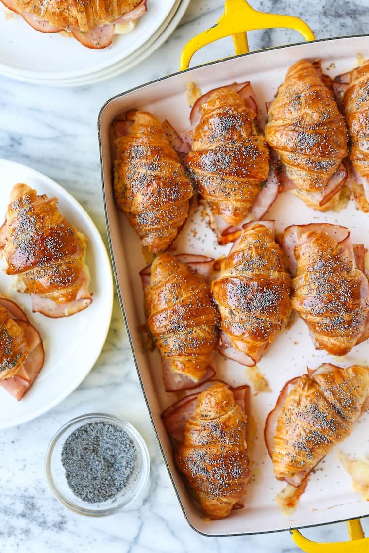 Baked ham and cheese croissants brushed with melted cheese and Dijon honey sauce on a baking pan. 