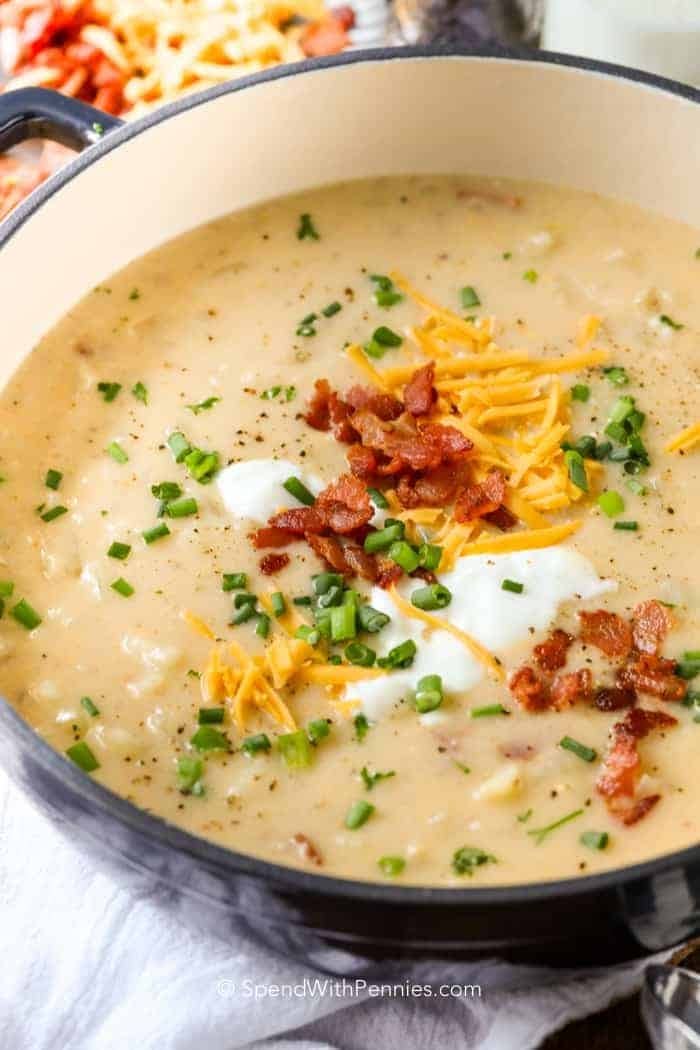 Potato soup in a pot with bacon bits, cheese and chives. 