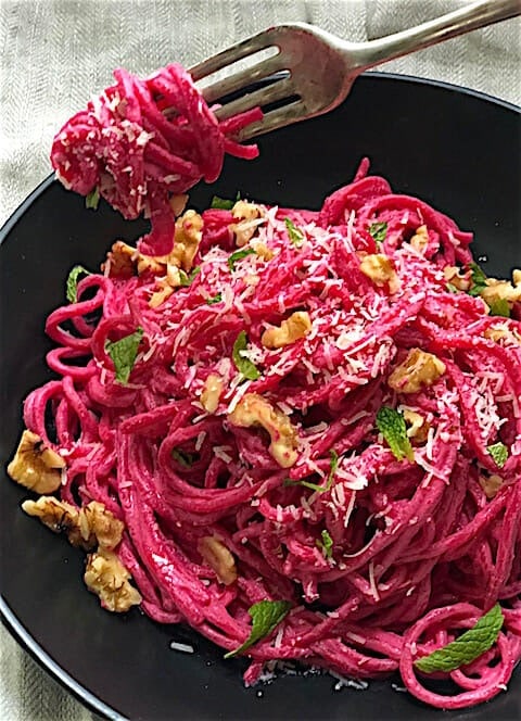 Pasta with beet sauce garnished with parmesan cheese and walnuts. 
