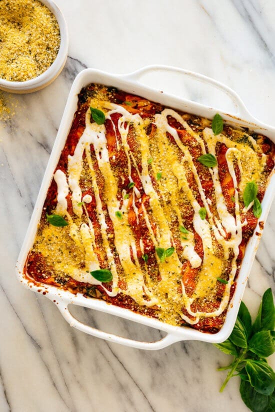 Lasagna in a casserole dish drizzled with cream sauce.