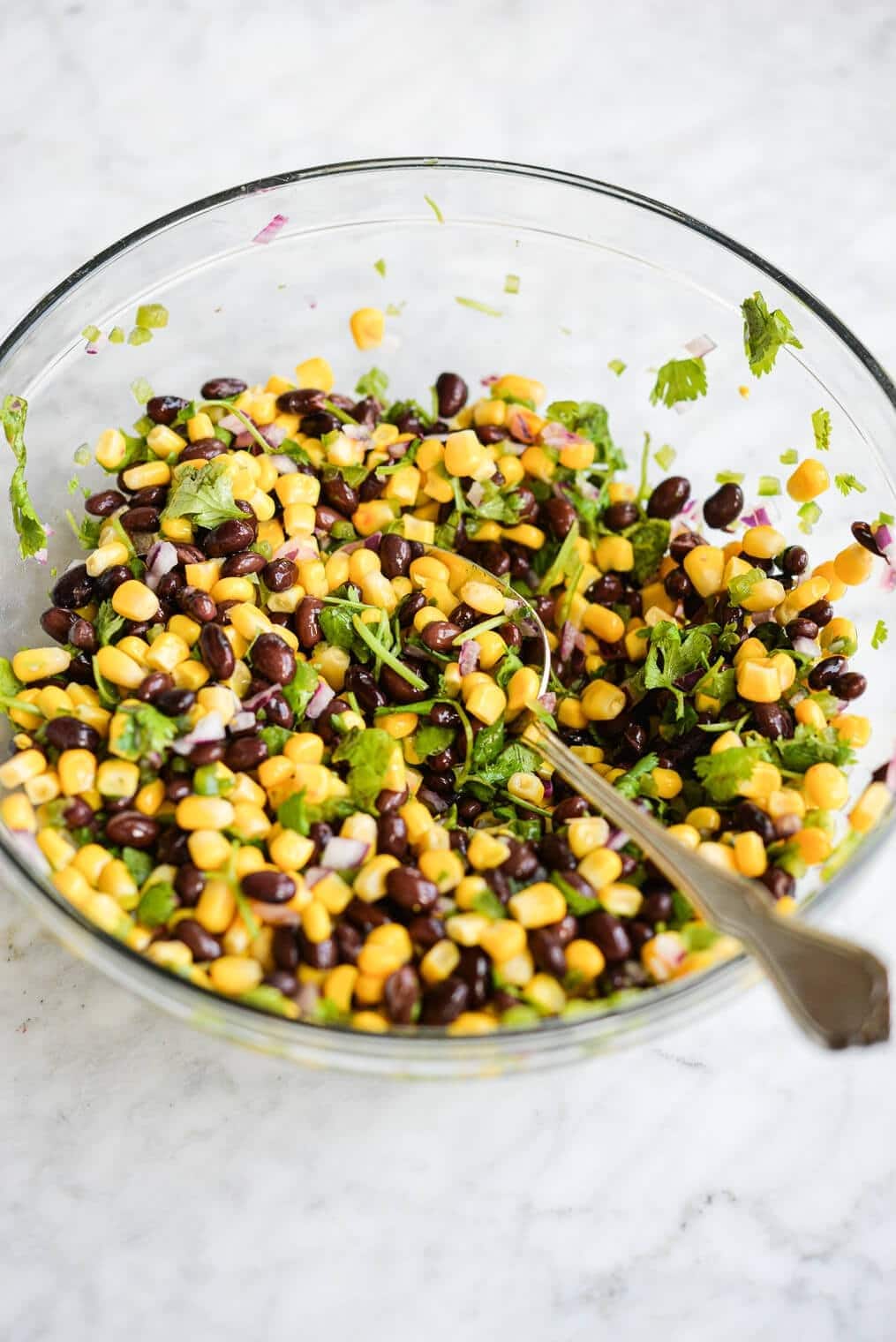 Black bean and corn salsa mixed on a clear glass bowl.