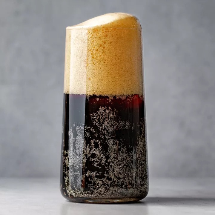 A glass of Black Velvet beer with foam in it.