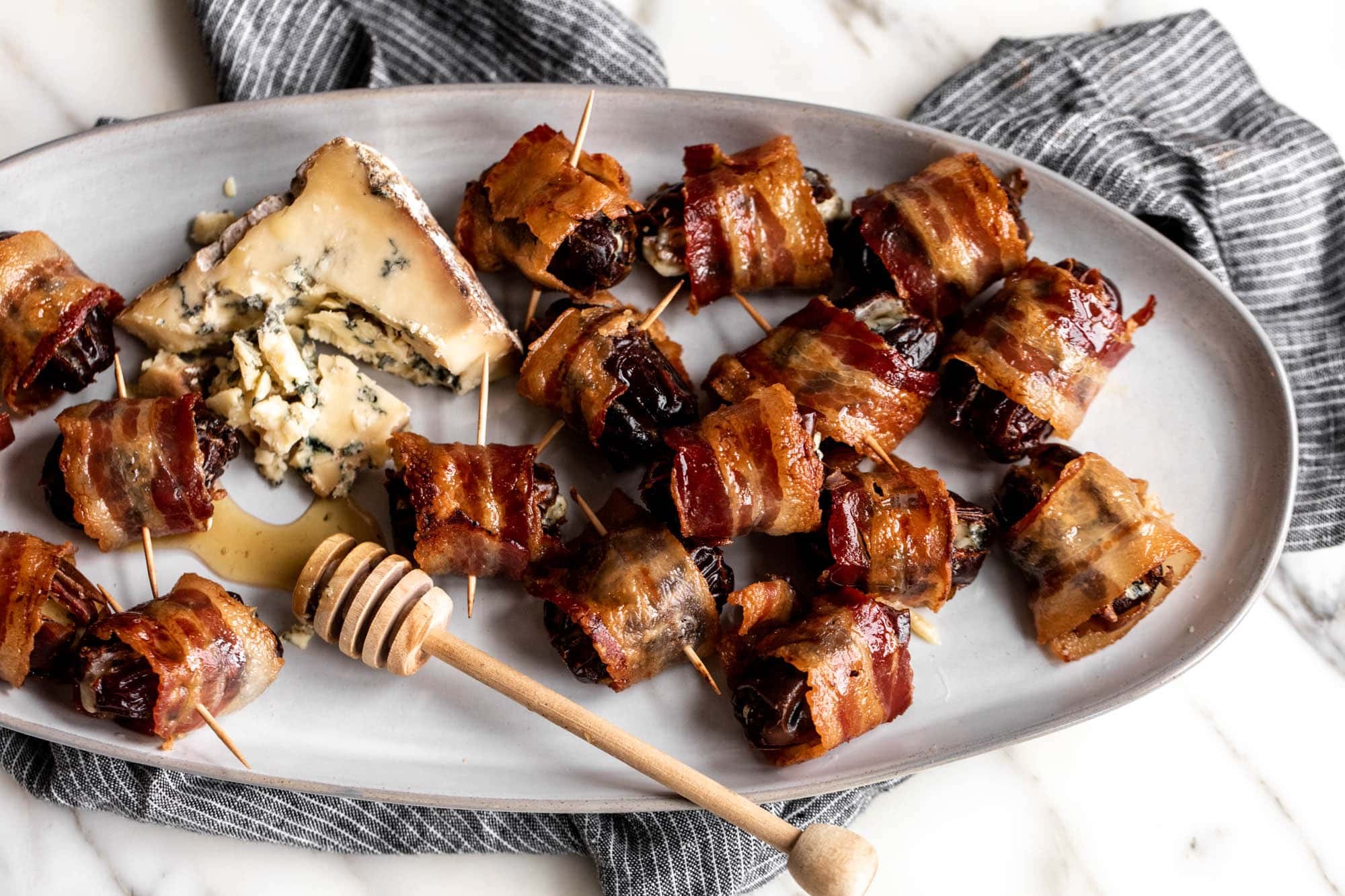 Bacon wrapped dates on stick with a serving of blue cheese on plate. 