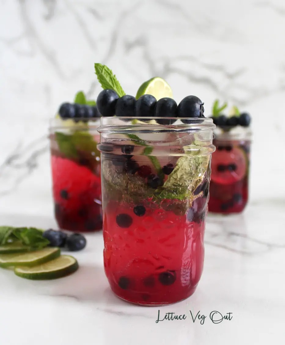Blueberry mocktail in a jar, garnished with lime and mint leaves.