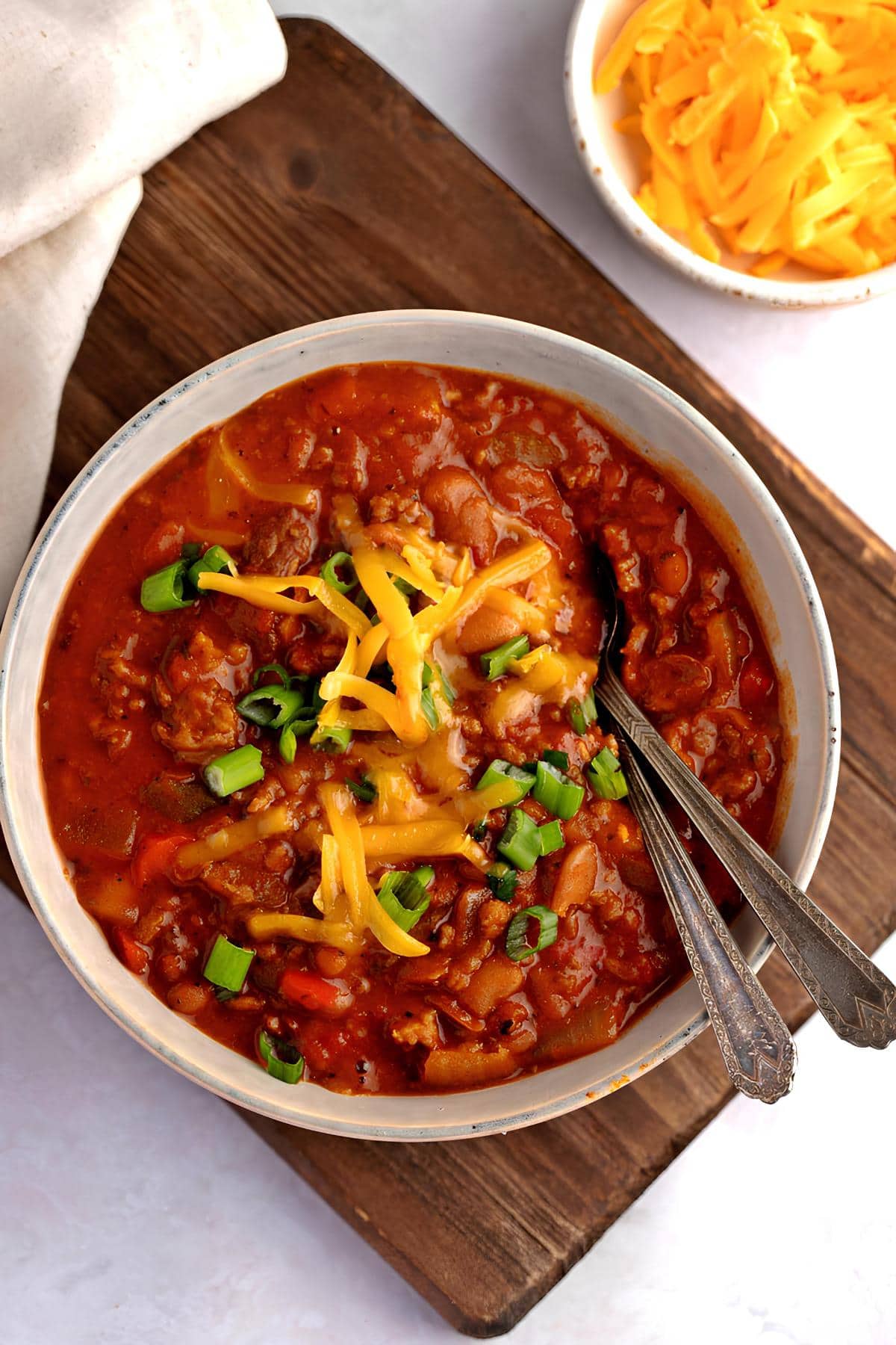 A bowl of comforting boilmaker chili with ground beef, beans, cheese and onions