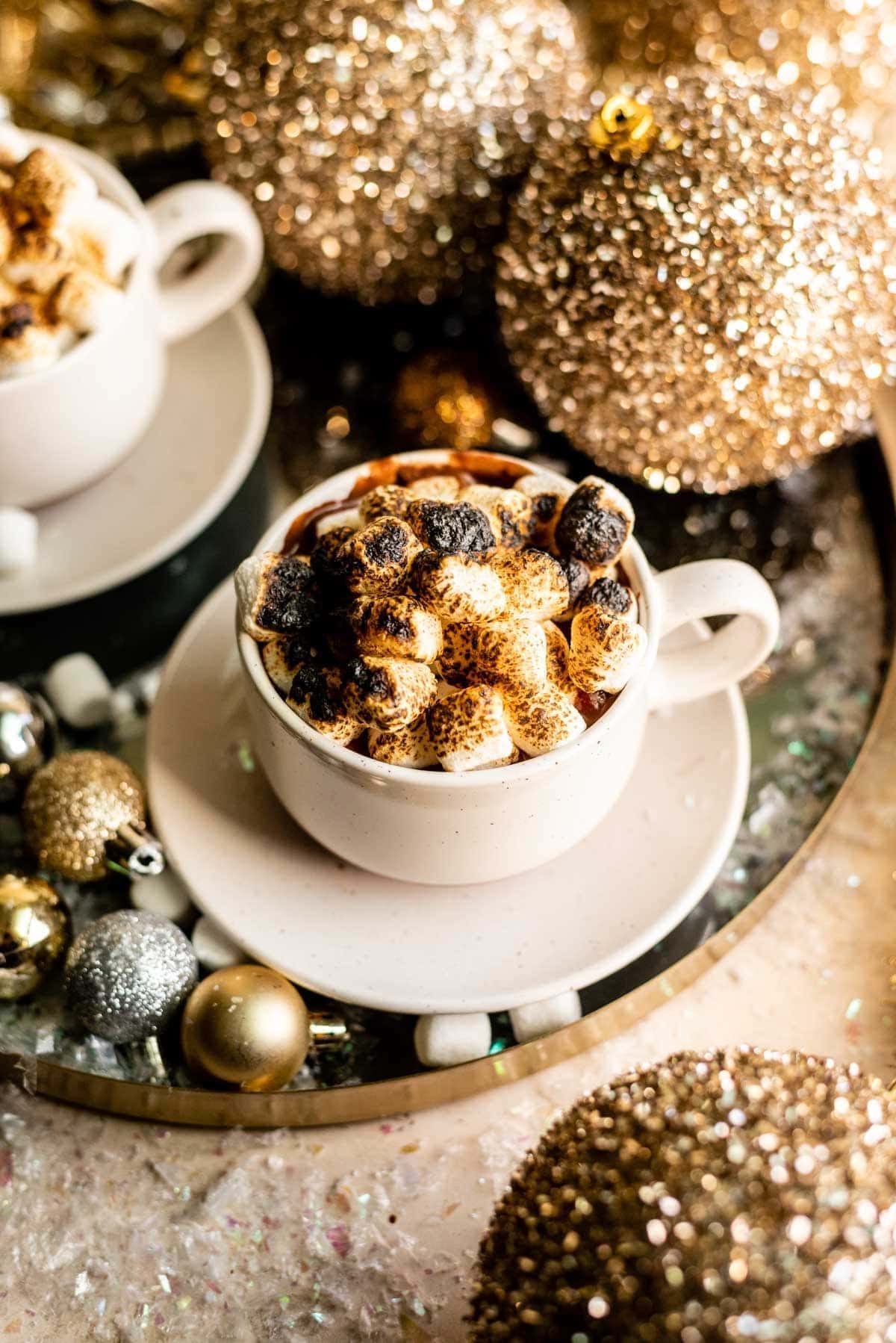 Drink in white mug topped with torched marshmallows on a festive table.