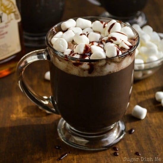Hot chocolate on a glass mug topped with marshmallows and chocolate drizzles. 