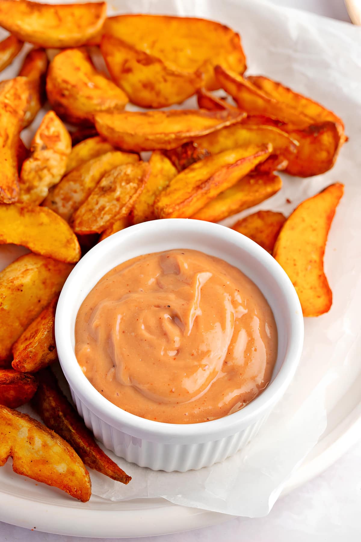 Bowl of dipping sauce with fried potato wedges.