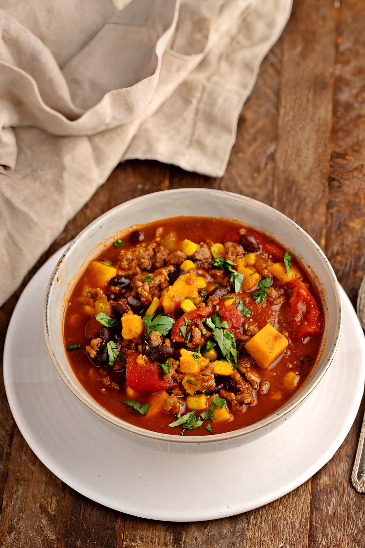 A bowl of sweet potato chili, garnished with fresh herbs, served hot and ready to be savored