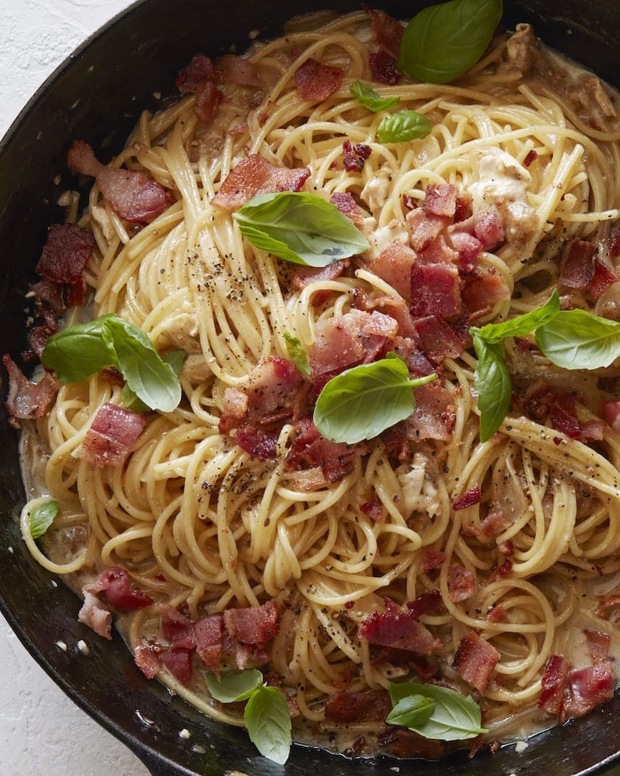 Pasta with brie, bacon and basil on a skillet