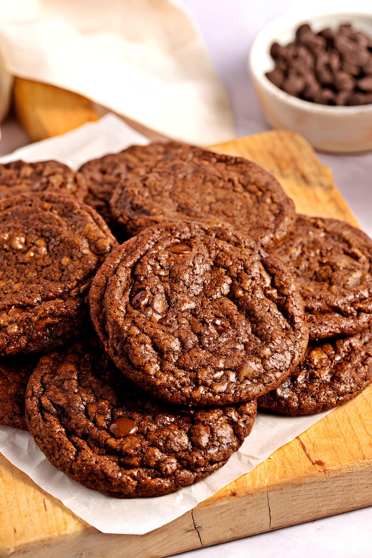 Bunch of chocolatey brownie cookies on a parchment paper on top of wooden board.