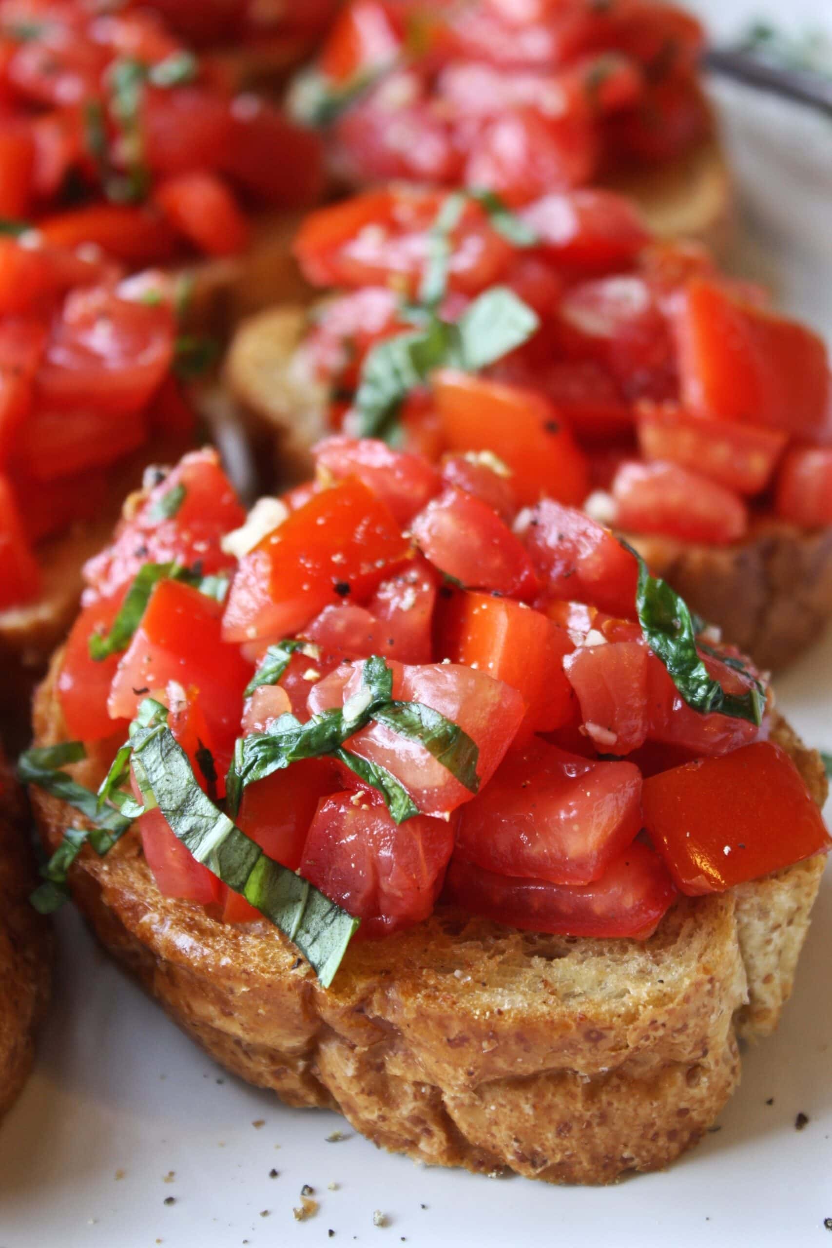 Pieces of toasted bruschetta topped with seasoned sliced tomatoes. 