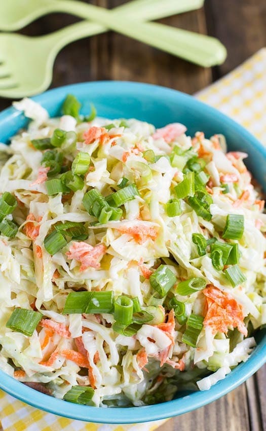 Bowl of coleslaw made with shredded cabbage, carrots, buttermilk, mayonnaise and sour cream, garnished with chopped green onions 