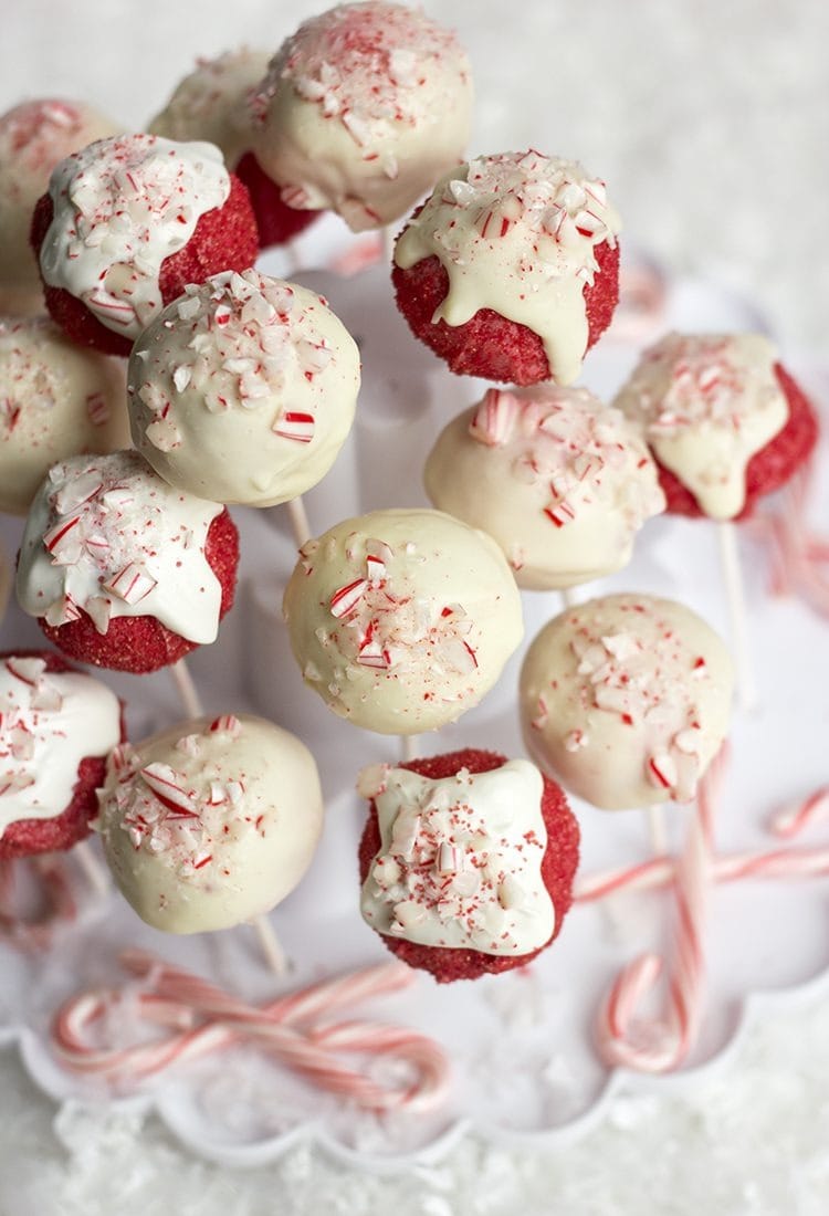 Red and white candy cake pops on stick sprinkled with crushed candy cane candies. 