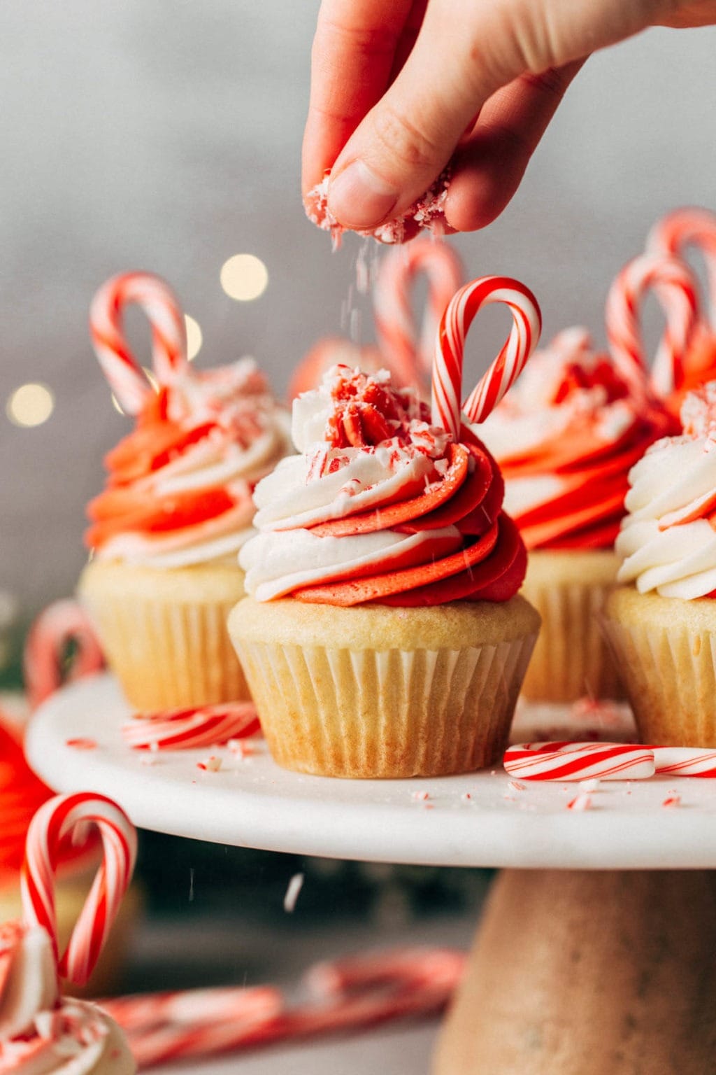 Cupcakes topped with red and white frosting and decorated with sugar cane candies.