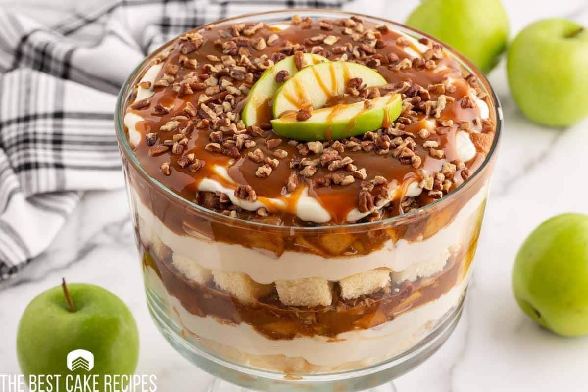 Apple cheesecake trifle made with layers of pound cake, fried apples, cheesecake filling, caramel, and pecans.