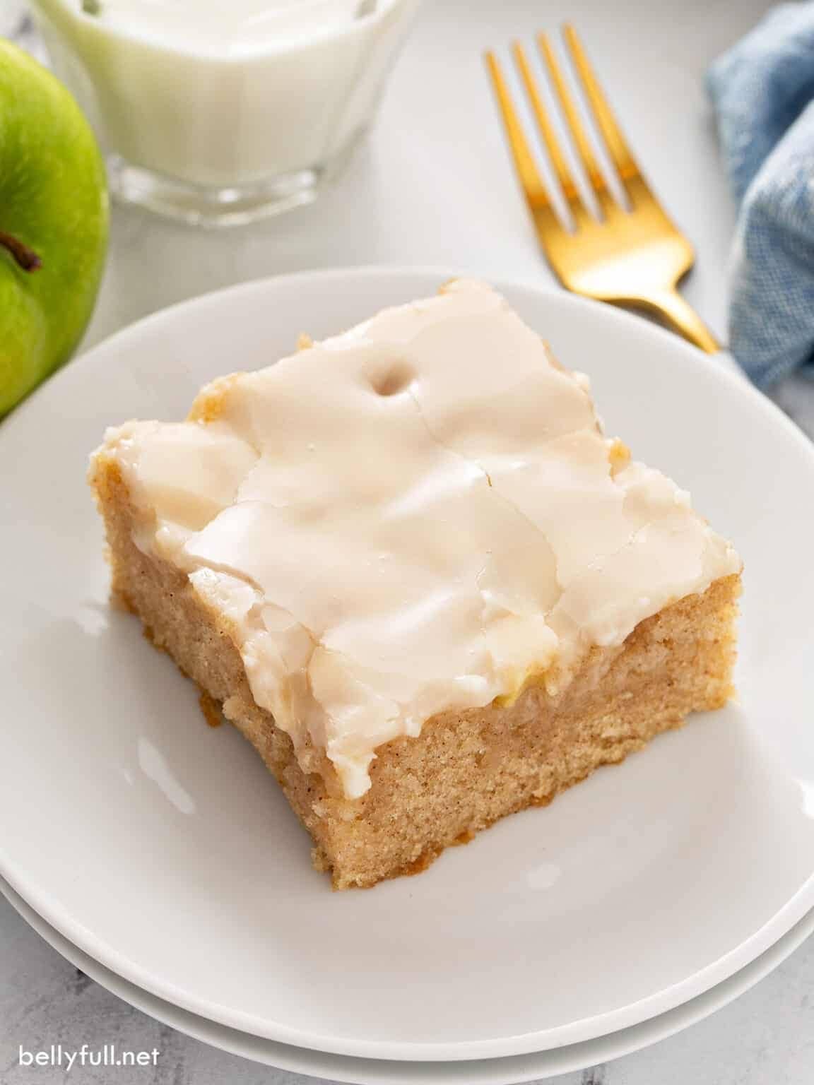 A piece of slice of apple sheet cake with sugar glaze served on a white dessert plate.