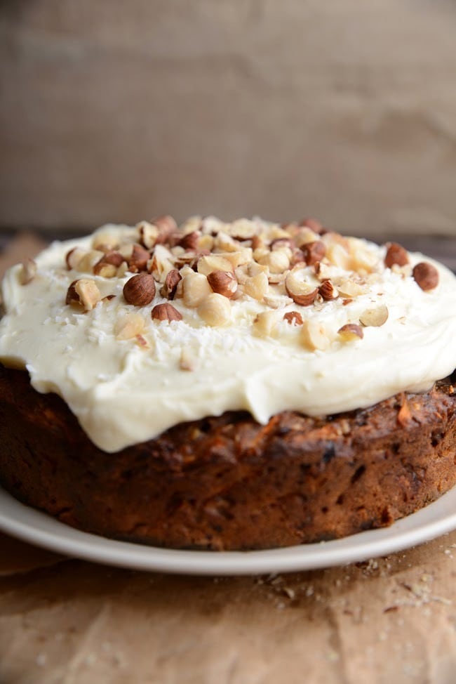 Round carrot cake topped with cream and chopped nuts. 