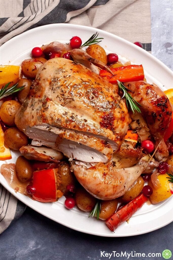 Whole baked chicken served with baked with potatoes, carrots, herbs cranberries and oranges.