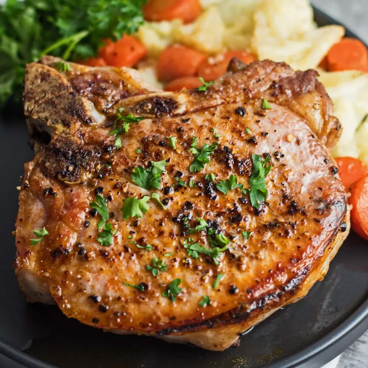 Seasoned with spices and herbs pork chops served with mashed potatoes and carrots. 