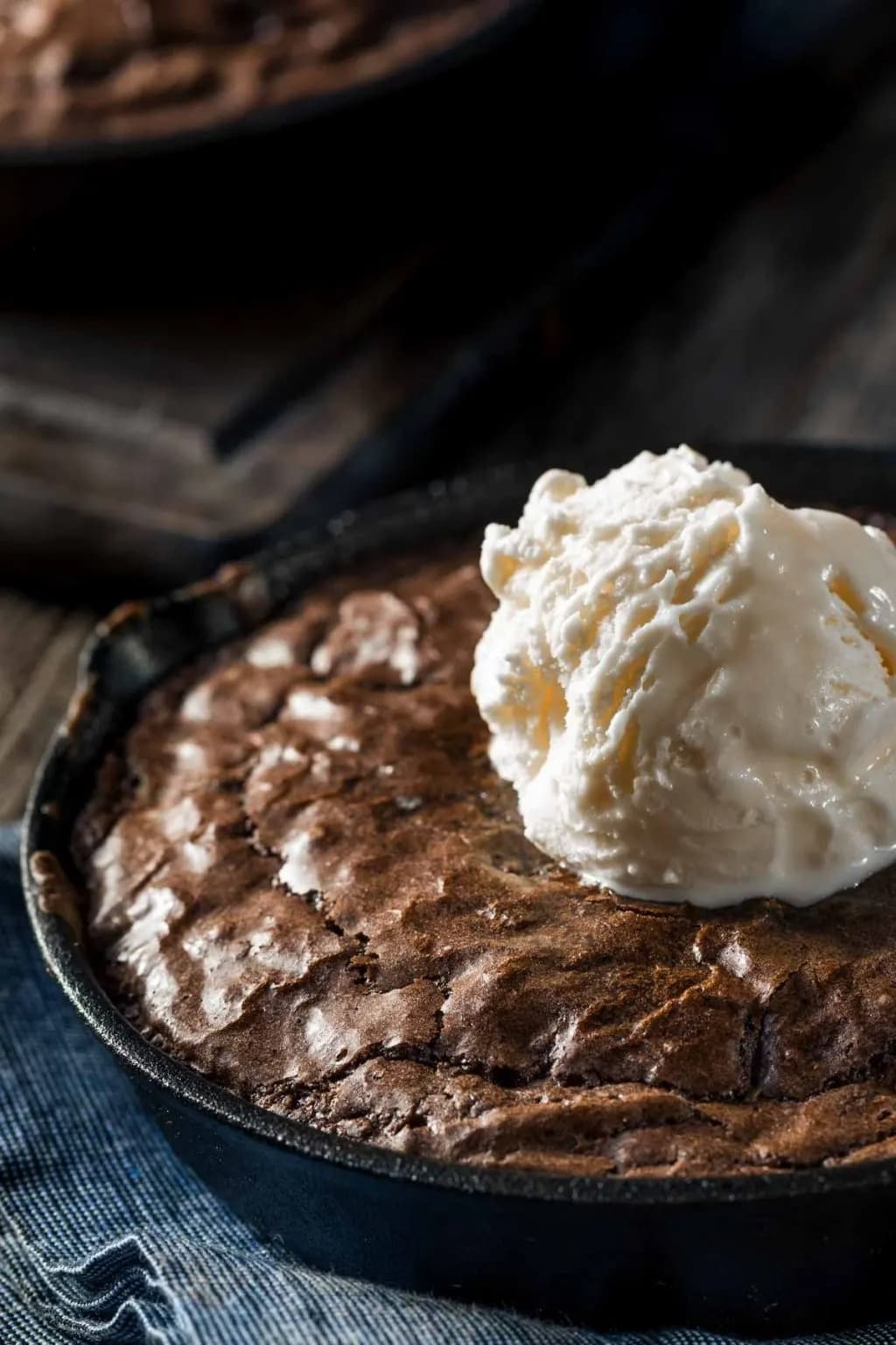 Brownies baked in a iron skillet topped with a scoop of vanilla ice cream. 