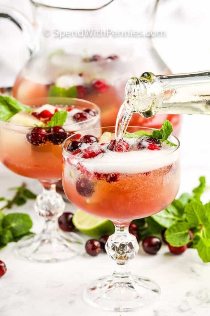 A refreshing champagne punch garnished with fresh mint leaves and cranberries.