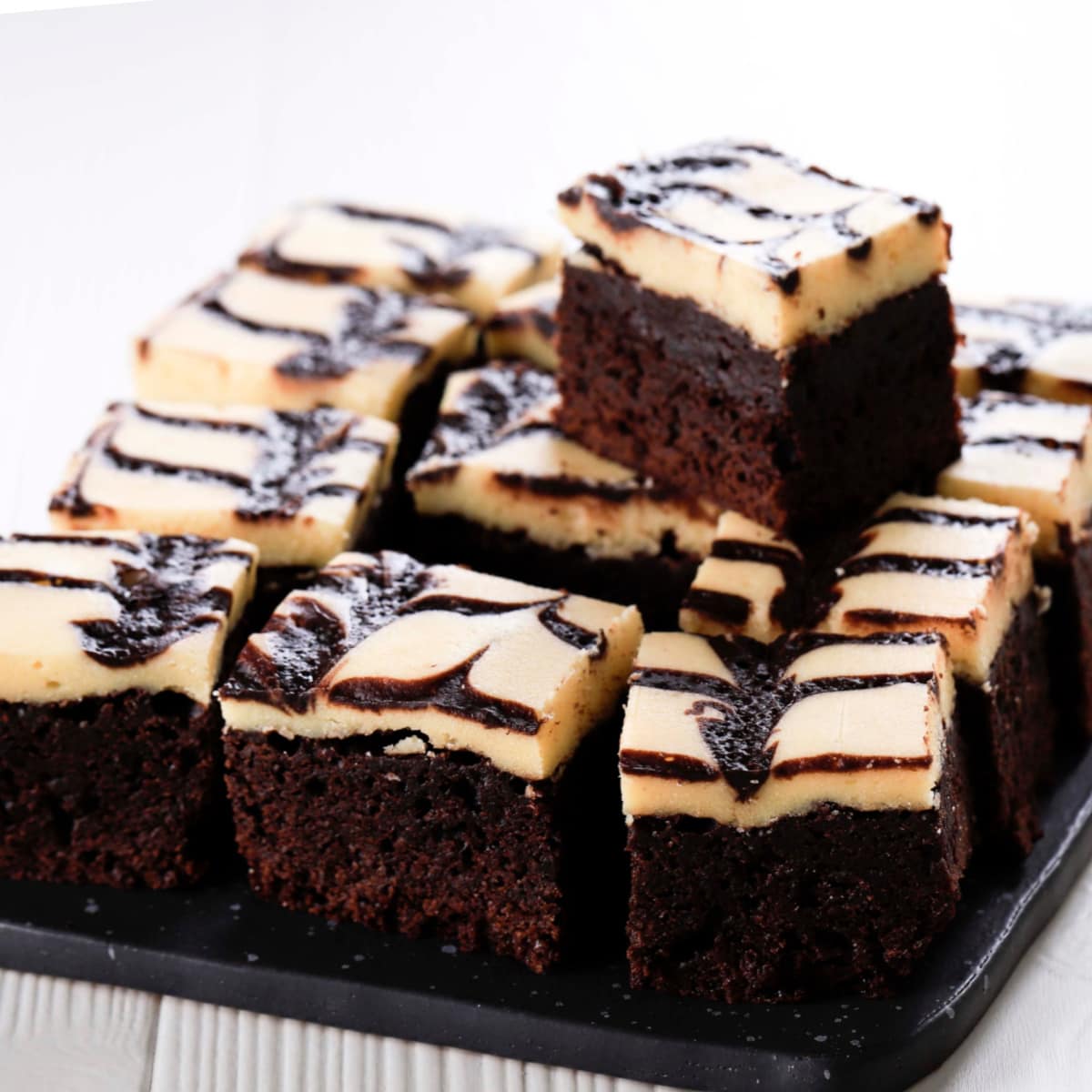 Cheesecake brownies sliced in square on a baking pan. 