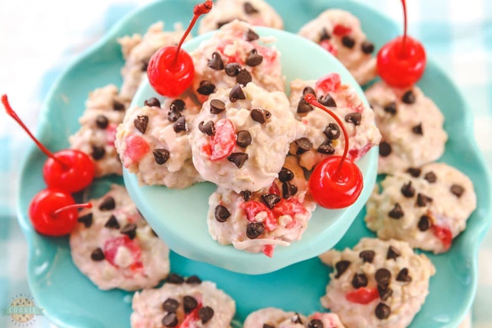 Top view of a bunch of  chocolate chip cookie dough on plate garnished with cherries. 