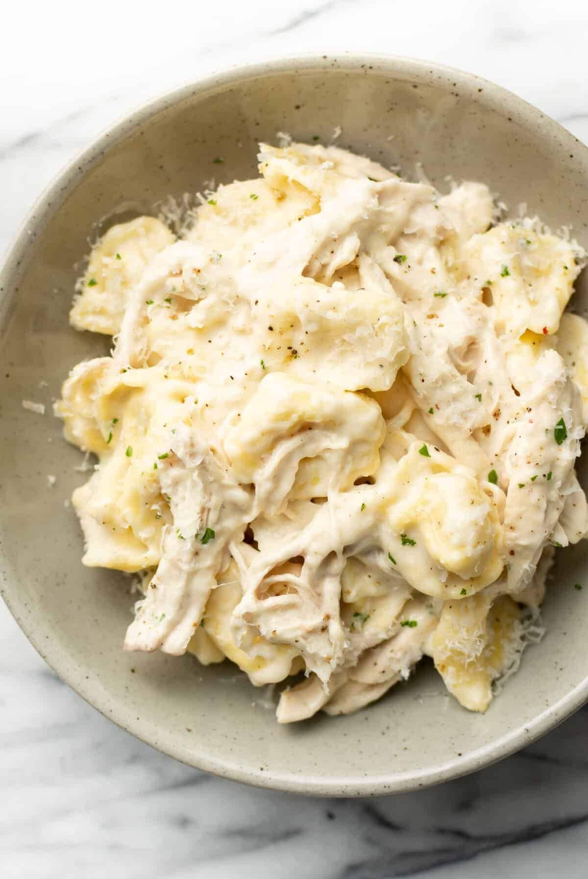 Creamy tortellini pasta with sauce and shredded chicken.