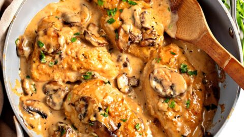 Chicken marsala served in pan with wooden spoon.