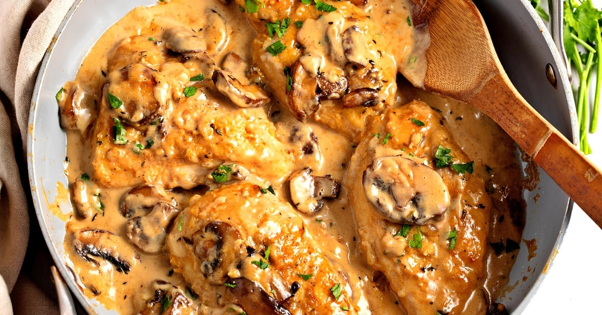 Chicken marsala served in pan with wooden spoon.