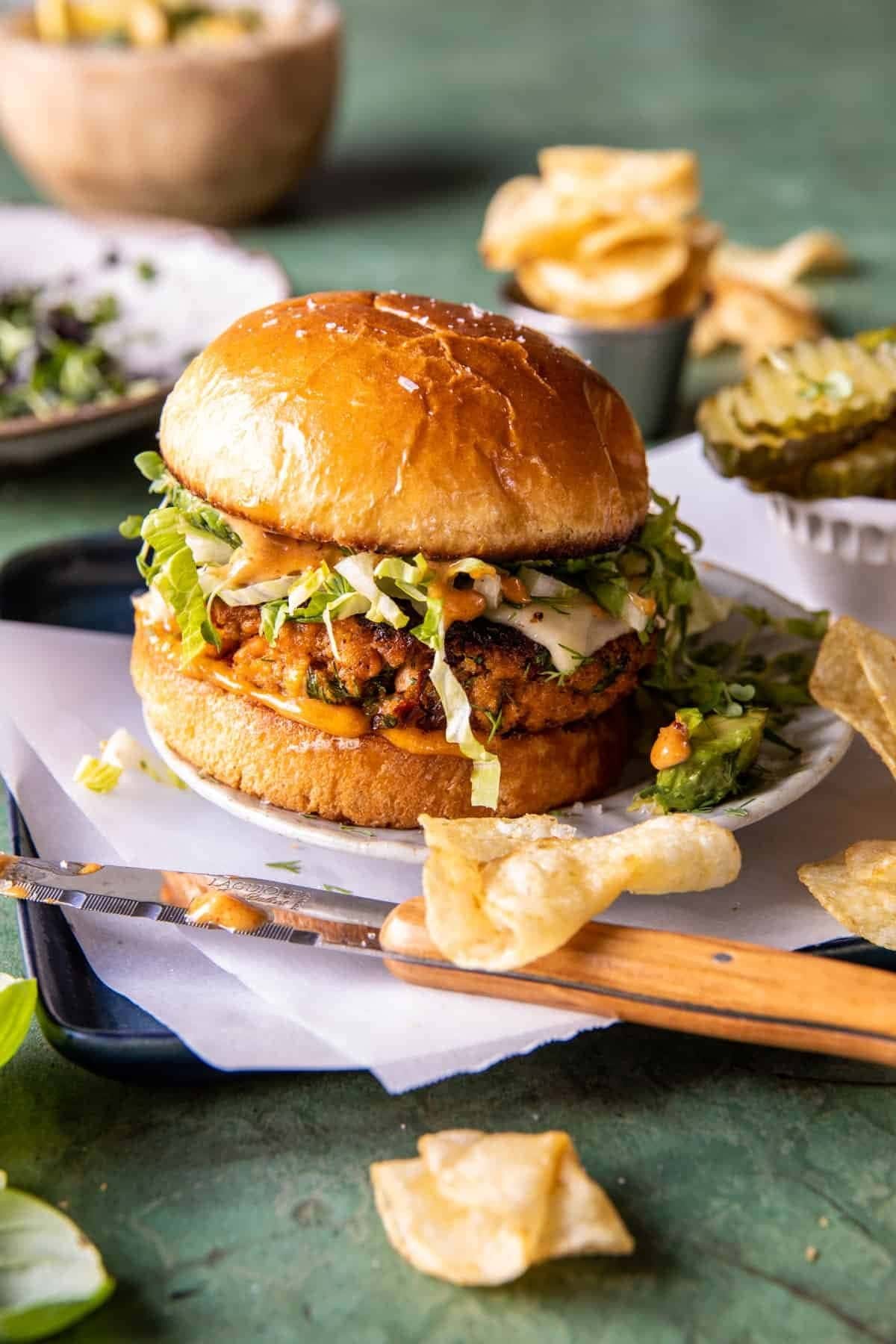 Pan-fried chipotle-seasoned salmon burgers sandwiched between toasted brioche buns with diced lettuce and creamy, spicy-sweet chipotle mayo