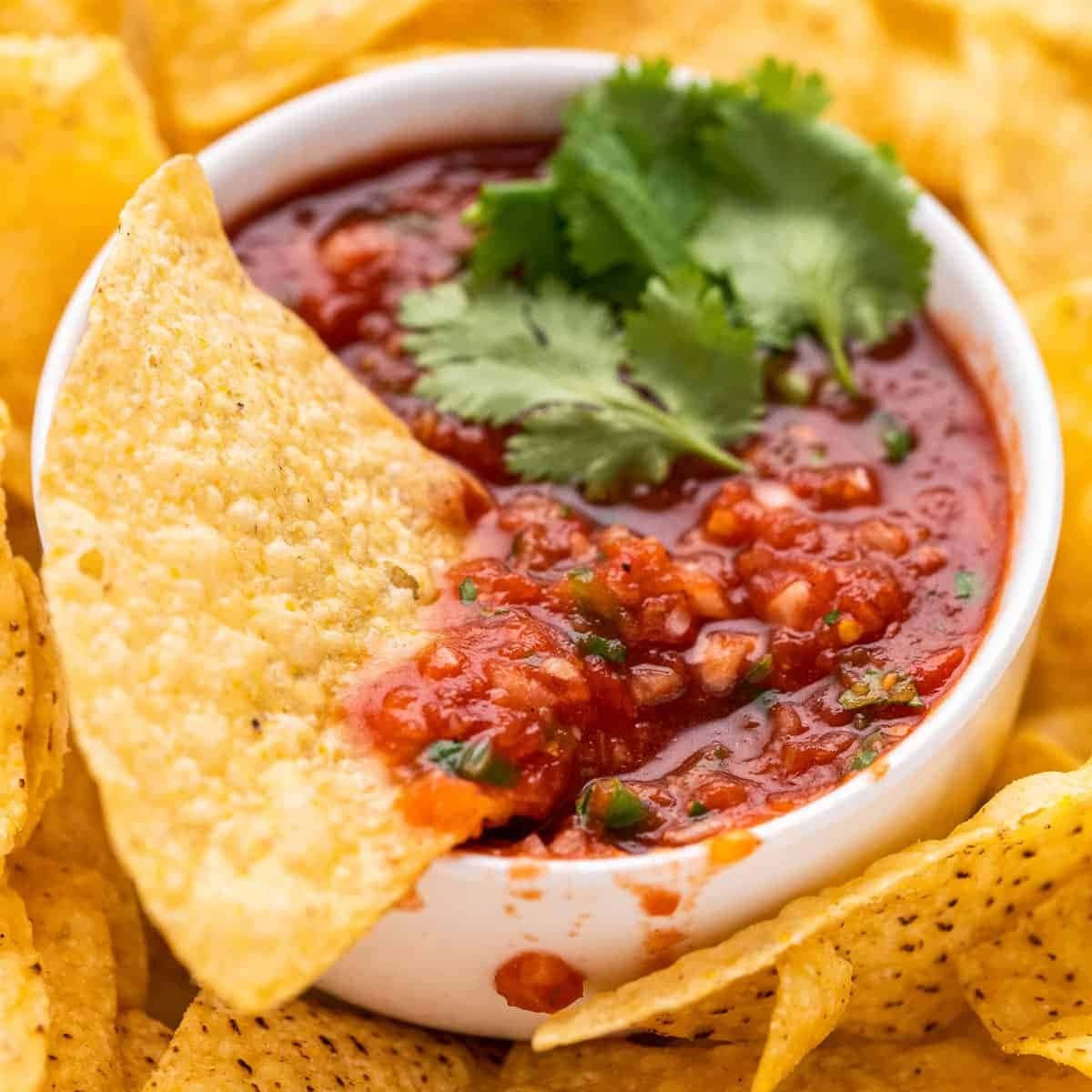 Bunch of chips served with salsa in a bowl. 