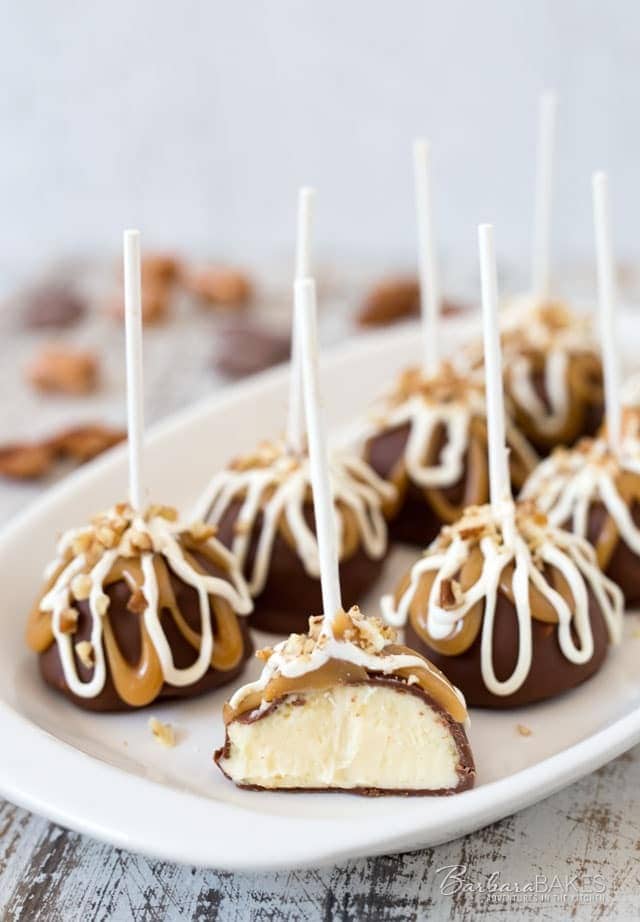 Chocolate covered cake pops on stick drizzled with caramel and white chocolate syrup. 