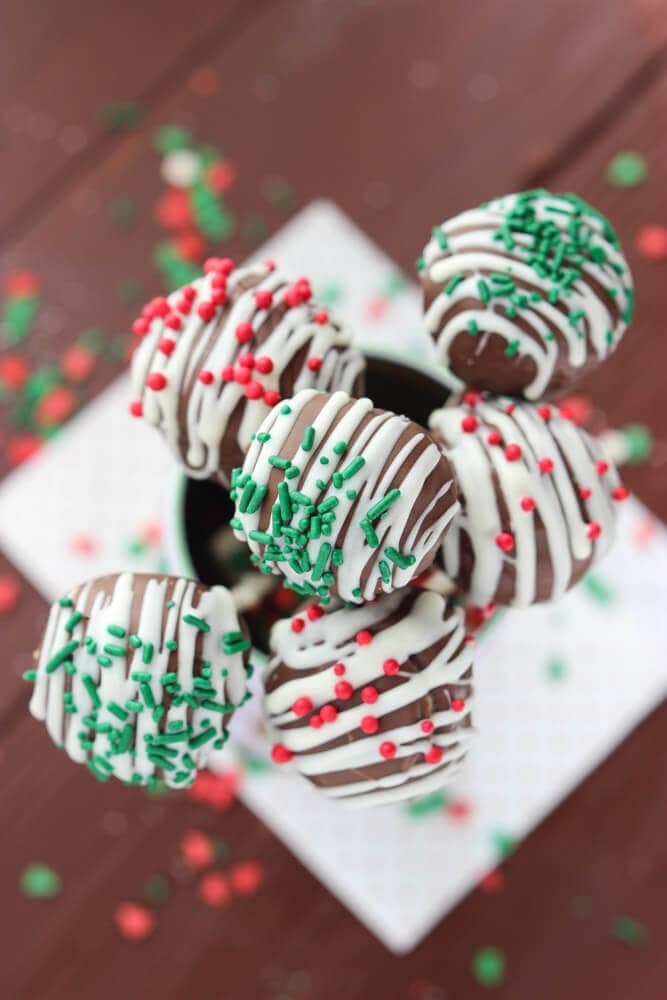 Chocolate cake pops covered with drizzled with white chocolate and sprinkles. 