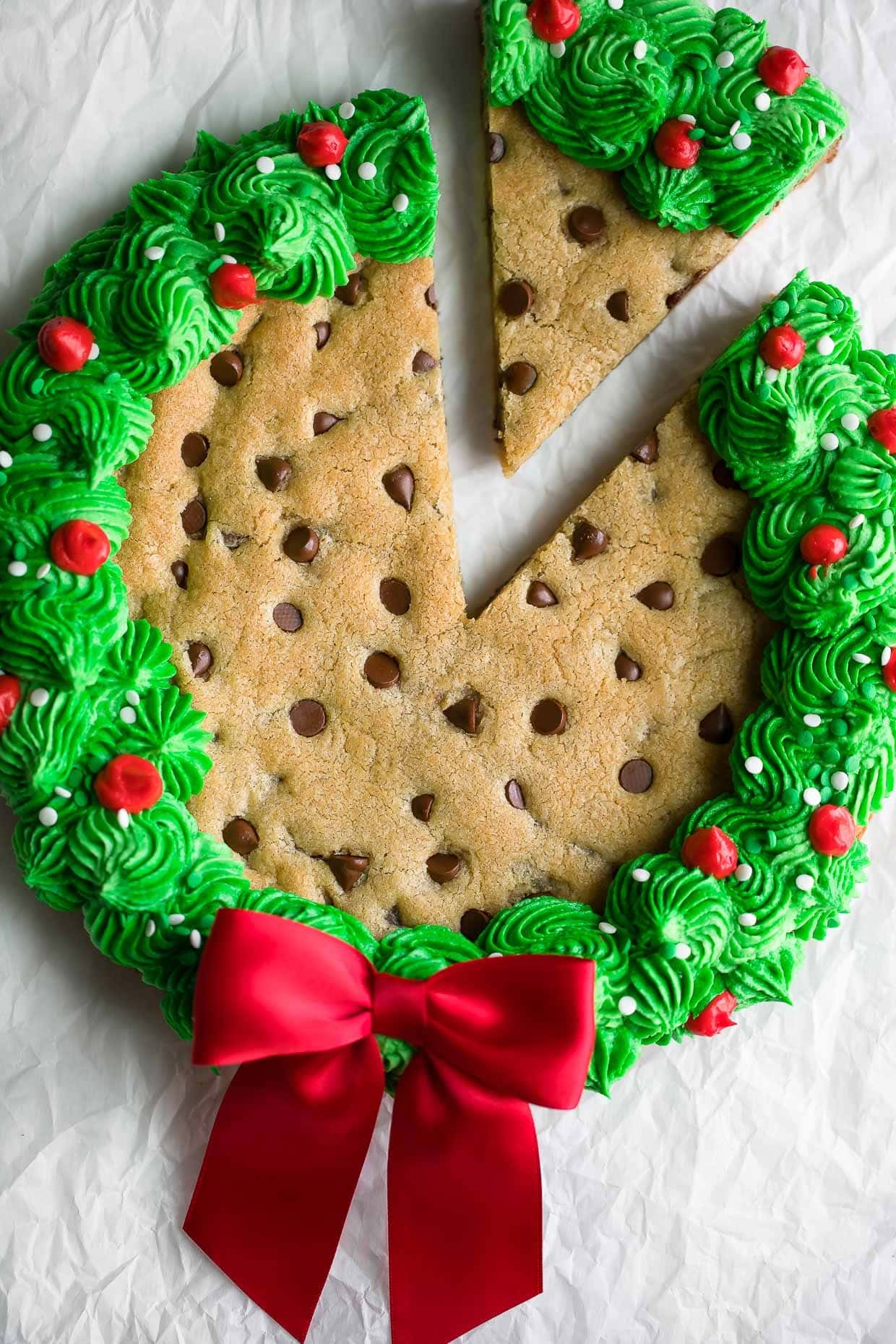 A cookie cake with green icing and a wreath design on top. 