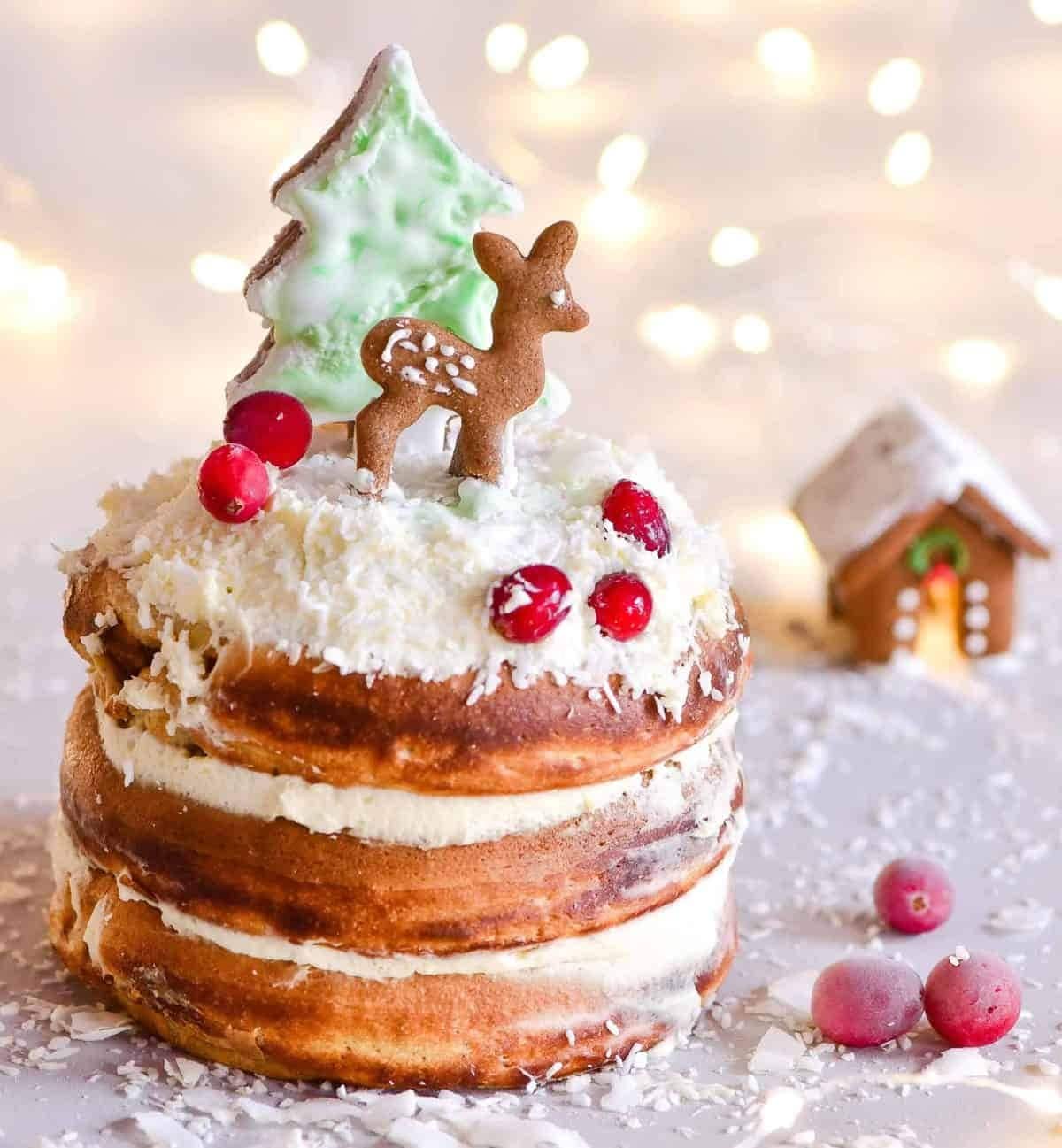 Stack of thick Gingerbread pancakes with cream filling topped with cranberries and cookies.