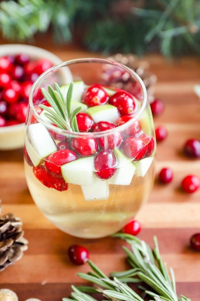 Sangria in a glass with chopped green apples, cranberries and rosemary. 